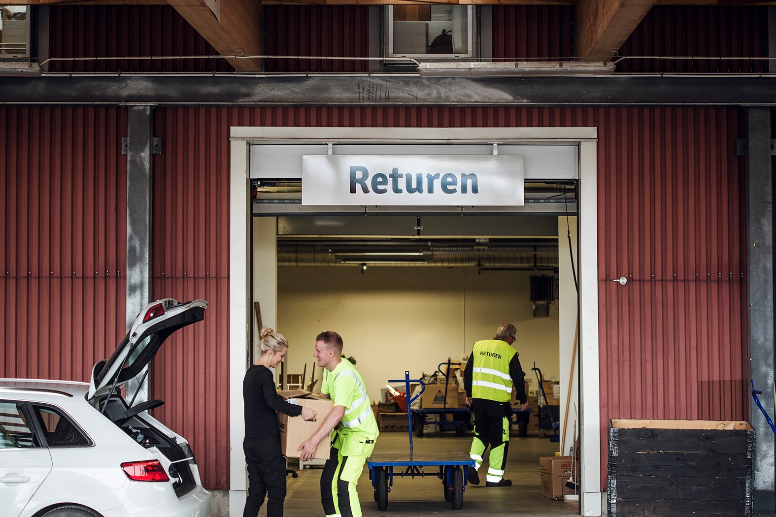 En person i Returen tar emot en kartong från en kund