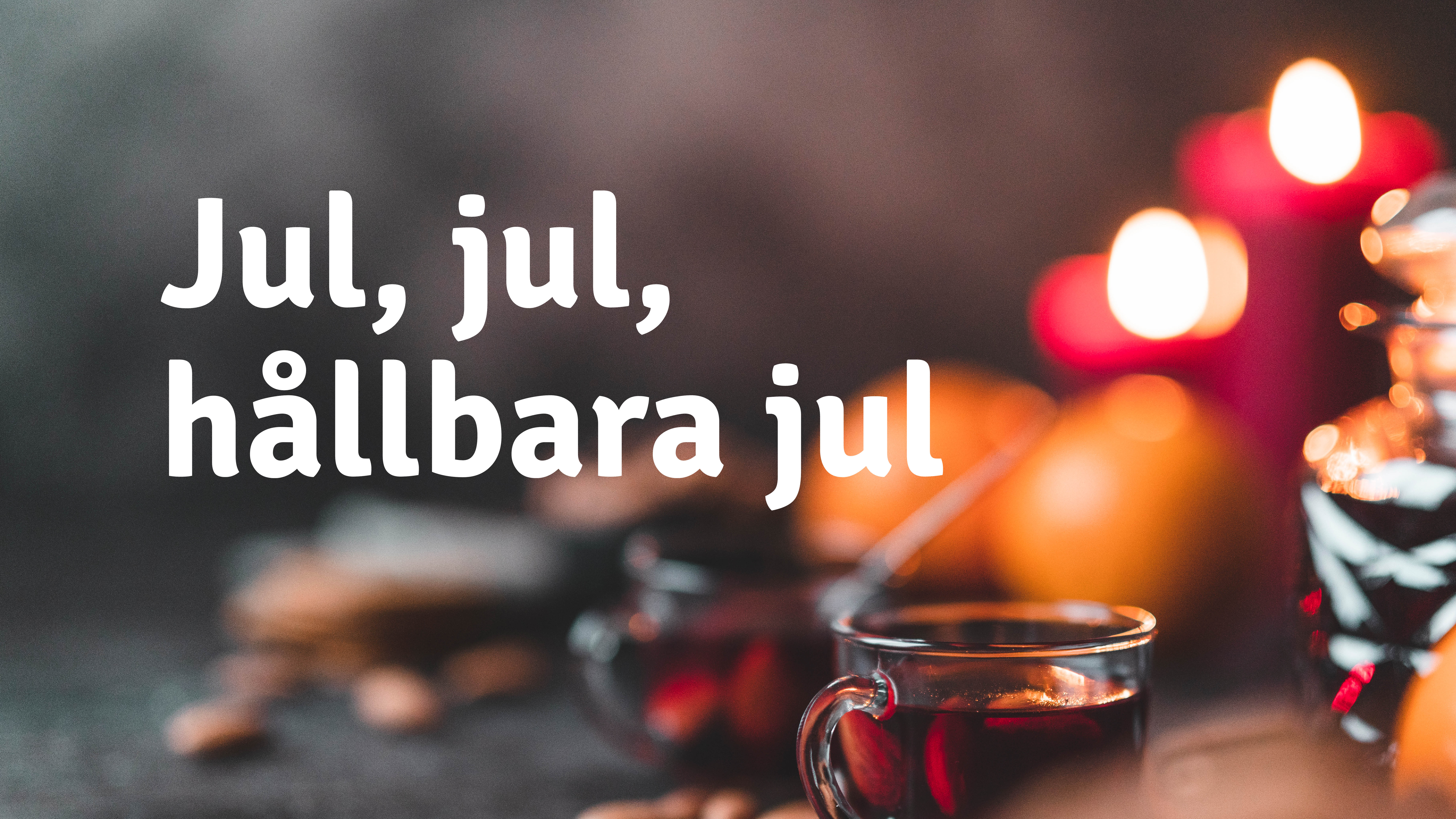 Julstämning med en full glöggmugg, apelsiner och brinnande ljus i bakgrunden.