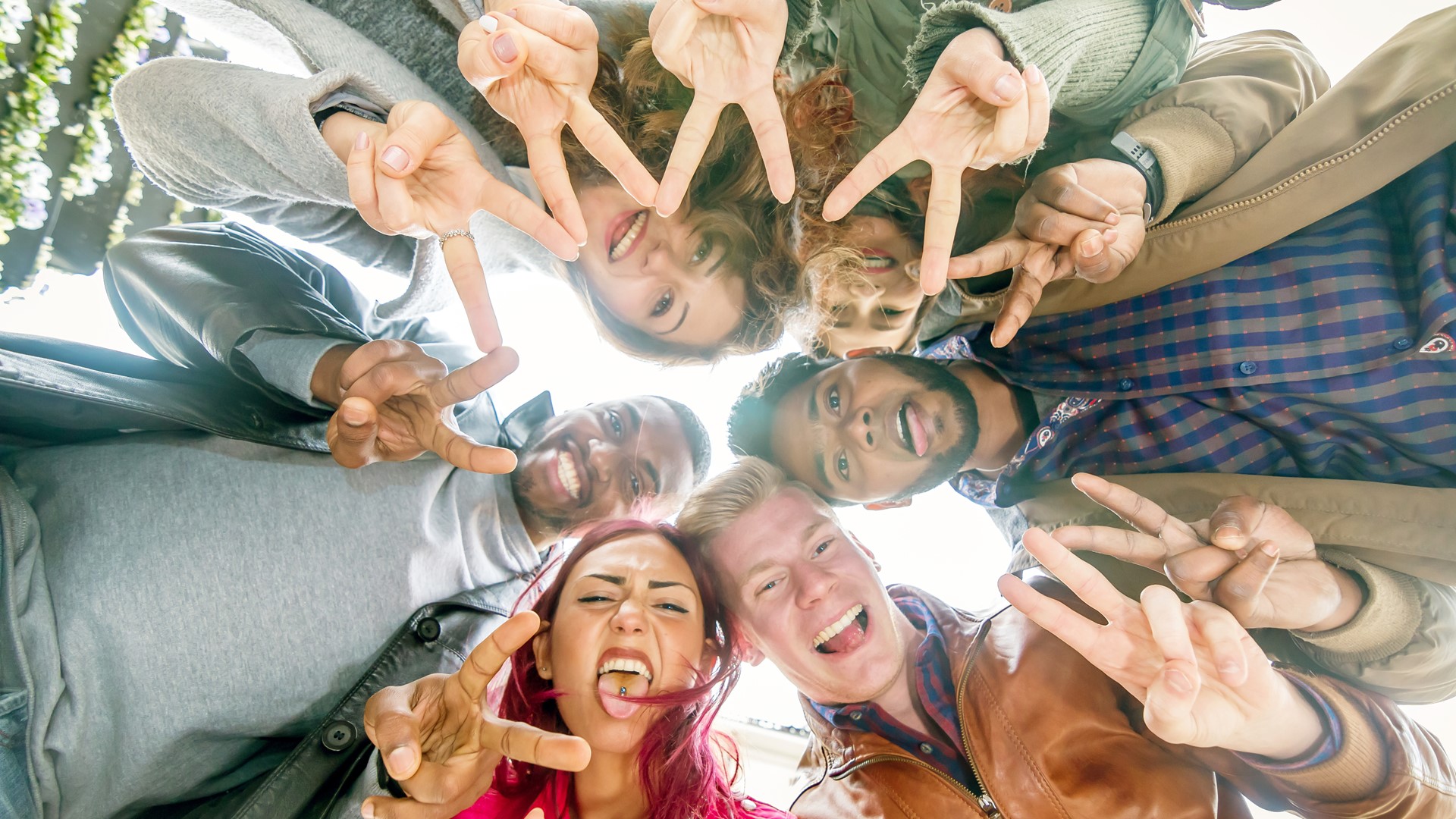 Sex ungdomar står i ring och gör v-tecken med händerna.